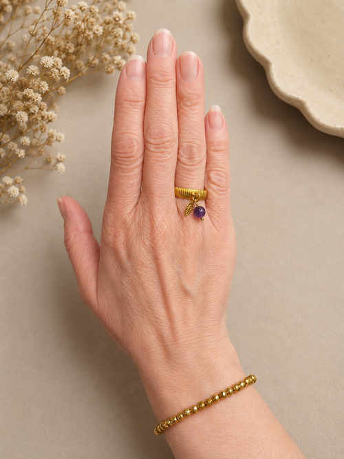Détail bague Lorca dorée avec améthyste portée au doigt